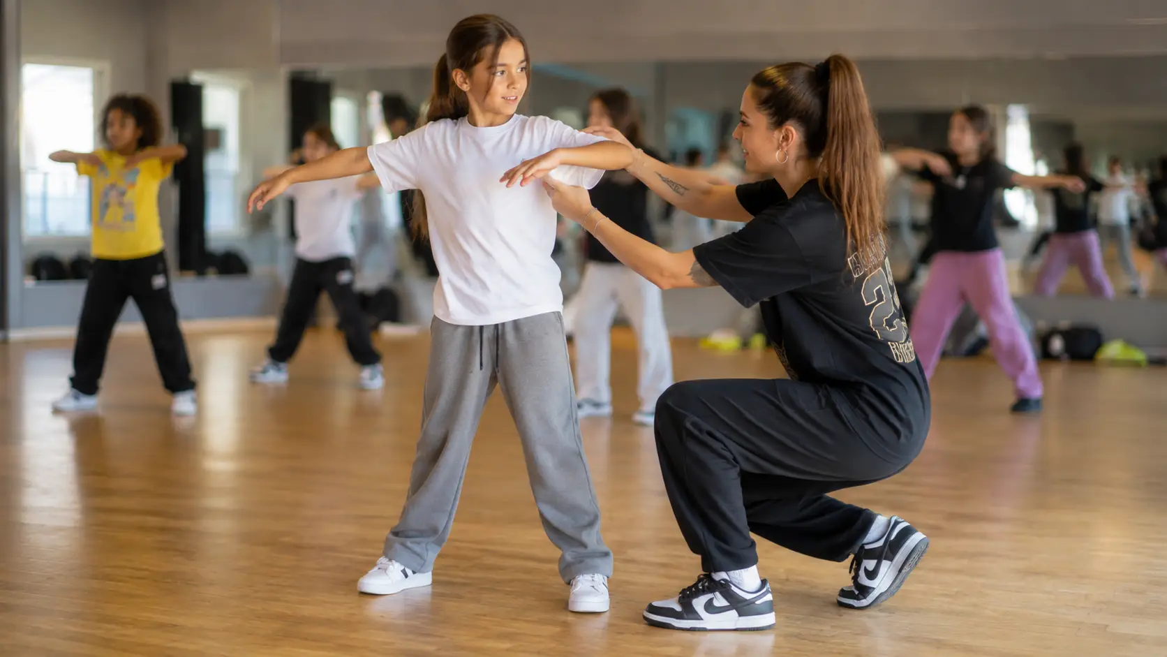 Profesora de baile corrigiendo la postura de los brazos a una niña