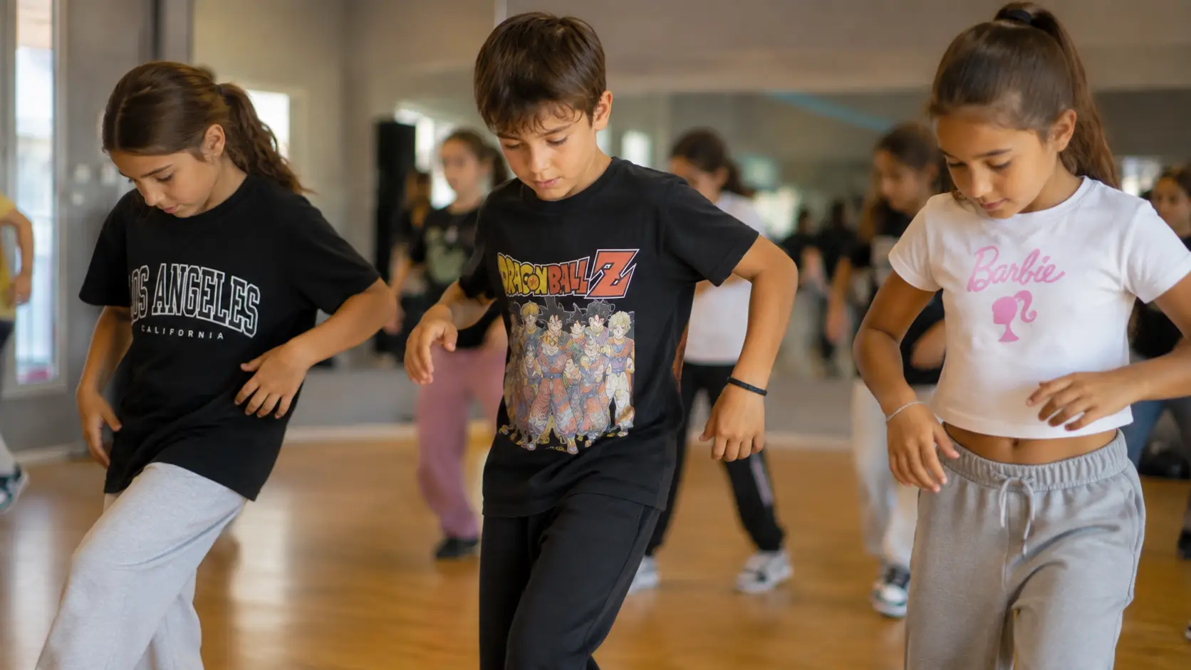 Tres niños concentrados aprendiendo un paso de baile urbano